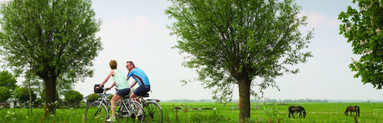 two people cycling in nature with animals in the background 