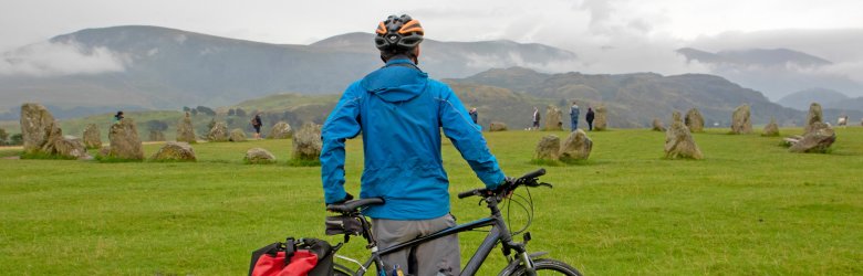 a man over looking a grass field leaning on his bike