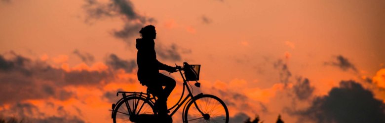 a person riding a bike into the sunset